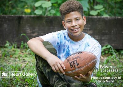 A boy with a tie-dye shirt in front of greenery