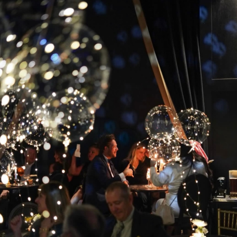 People seated in formal wear at tables inside event venue