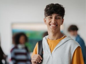 Teen stands smiling with backpack