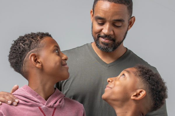 Family standing together, two boys smiling at father